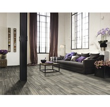 Woonkamer met grijze houten vloer, bank en grote ramen