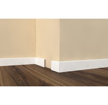 Hoek van de kamer met witte plinten en houten vloer