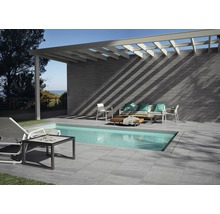Terras met zwembad, tegelvloer, wandbekleding en zithoek onder een pergola.
