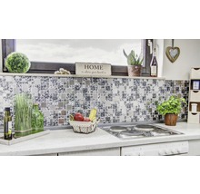 Detailopname van een moderne keuken met mozaïektegels als spatwand, kookplaat en diverse decoraties.