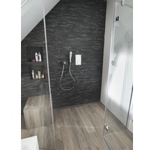 Badkamer met douche, stenen muur en houten vloer.