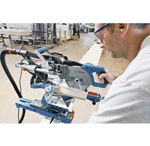 Een persoon bedient een Bosch afkort- en verstekzaag bij het zagen van een werkstuk.