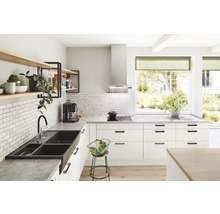 Lichte keuken met spoelbak, kraan, rekken en keukenapparatuur.