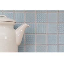 Decoratieve vierkante wandtegels met patronen achter een theepot