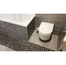 Badkamer met bad, toilet en stenen vloer