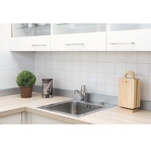Keukenscène met spoelbak, kraan, snijplanken en decoratie op een licht aanrechtblad voor een witte tegelwand