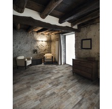 Rustieke kamer met houten balkenplafond, stenen muren, houten vloerdelen, dressoir en fauteuils.