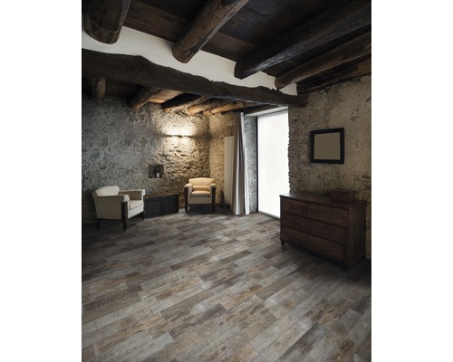 Rustieke kamer met houten balkenplafond, stenen muren, houten vloerdelen, dressoir en fauteuils.