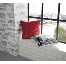 Decoratief interieur met een rood en een zwart-wit kussen op een vensterbank voor een muur bedrukt met stadsnamen