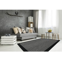 Woonkamer met grijze bank, kussens, houten tafel, grijs tapijt en decoratie