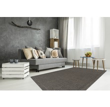 Woonkamer met grijze bank, kussens, salontafel van houten kisten, vloerkleed en decoratieve elementen