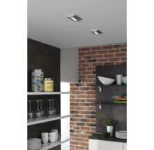 Keukenscène met plafondspots, bakstenen muur en open planken met servies