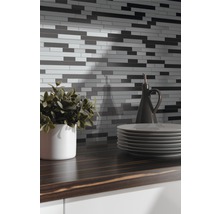 Mozaïektegelwand boven een aanrecht met servies en decoratie
