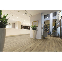 Lichte ontvangstruimte met houten vloer, planten en zitplaatsen.
