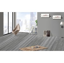 Lichte kamer met grijze houten vloer, fauteuil en vloerkleed