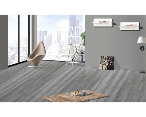 Lichte kamer met grijze houten vloer, fauteuil en vloerkleed