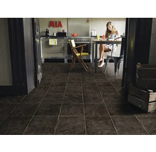 Moderne keuken met donkere tegelvloer en een vrouw aan de eettafel.