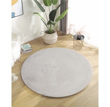Inrichting met rond kunstvezel tapijt op een houten vloer in een heldere ruimte.