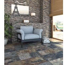 Woonkamer met natuurstenen muur en vloertegels met steenlook, fauteuil en decoratie