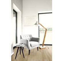 Lichte woonkamer met fauteuil, staande lamp en kleine tafel op houten vloer