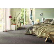 Moderne slaapkamer met grijs tapijt, bed met beddengoed met patroon en witte nachtkastjes.