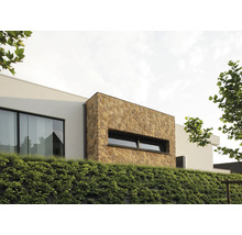 Buitenaanzicht van een modern huis met natuurstenen gevel en een begroeide helling