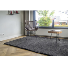 Grijs tapijt in de woonkamer met stoel en bijzettafel bij het raam.