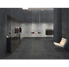 Modern interieur met donkere tegels op vloer en wanden, kledingrekken en zitmogelijkheid.