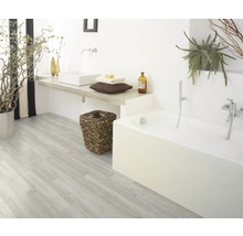 Badkamer met bad, wastafel, houten vloer en planten