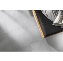 Lichte tegelvloer naast een bed