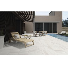 Terras met tegels, ligstoel, tafel en stoelen naast een zwembad.