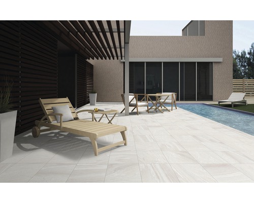 Terras met tegels, ligstoel, tafel en stoelen naast een zwembad.