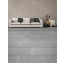 Lichte woonkamer met vloertegels, bank en decoraties.