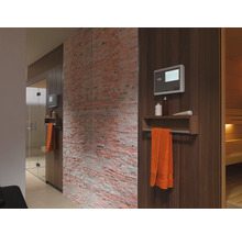 Interieur van een sauna met houten panelen, handdoek, bediening en decoratieve bakstenen muur