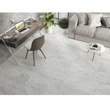 Lichte woonkamer met tegelvloer in marmerlook, bureau, bank en planten.