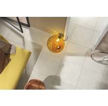 Overzicht van een kamer met vloertegels, lamp, bank en fiets