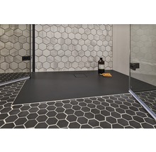 Gelijkvloerse douche met zwart douchegedeelte en zeshoekige tegels op de wand en vloer.