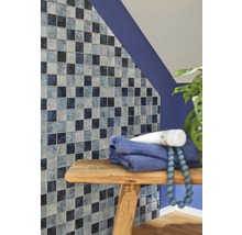 Badkamerwand met mozaïektegels in verschillende blauwtinten, handdoek en decoratie op een houten kruk.