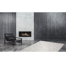 Woonkamer met fauteuil, vloerkleed en open haard.