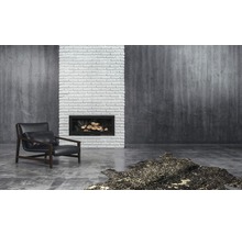 Woonkamer met fauteuil, open haard, stenen muur en vloerkleed