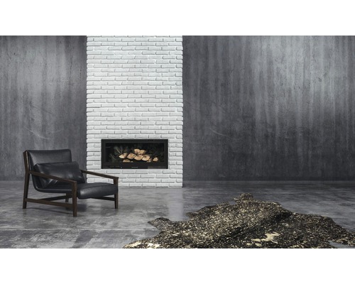 Woonkamer met fauteuil, open haard, stenen muur en vloerkleed