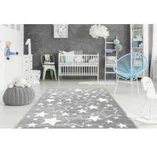 Kinderkamer met grijs tapijt met witte sterren, babybed, commode en speelgoed.