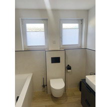 Lichte badkamer met toilet, wastafel, bad en twee ramen met plisségordijnen
