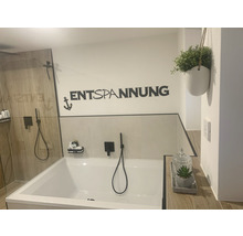 Badkamer met bad, douche, wanddecoratie met het opschrift Ontspanning en een plant