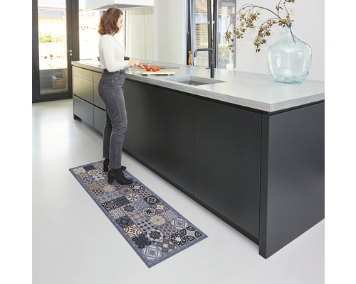 Vrouw staat in de keuken op een keukenmat met patroon.