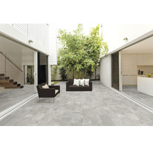 Licht terras met grijze vloerplaten, zitmeubelen en beplanting
