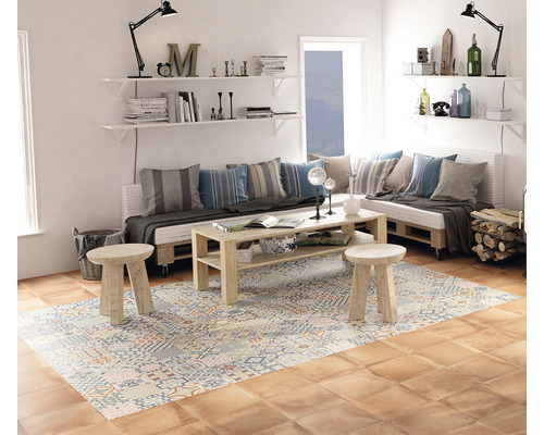 Woonkamer met zithoek van pallets, houten tafel, een vloerkleed met motief en een houten vloer