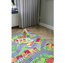 Speelkleed met stratenpatroon, houten vogelhuisje en houten puzzel op de vloer.