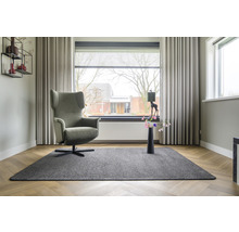 Woonkamer met fauteuil, tapijt en raamdecoratie