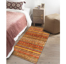Scene met bed, nachtkastje en veelkleurig vloerkleed in etnische stijl